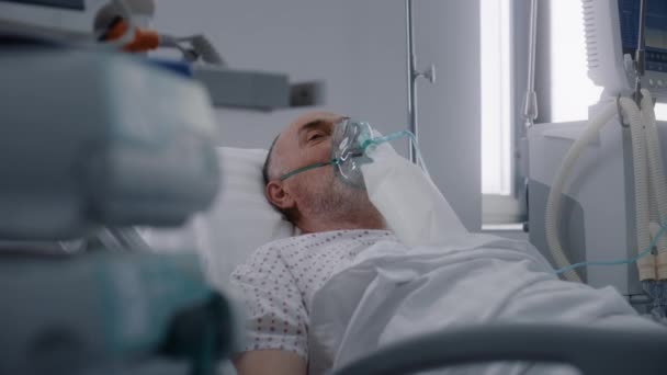 医院有现代化设备的急救室 戴氧气面罩的老人在手术成功后躺在床上 护士照顾病人 医疗设施内的重症监护科 — 图库视频影像