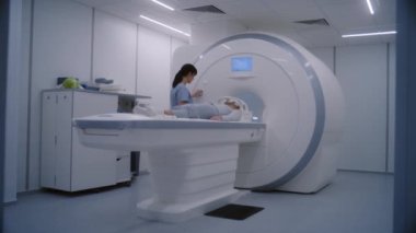 Kadın hasta MRI ya da CT tarama yatağında yatıyor makineden hareket ediyor ve muayeneden sonra ayağa kalkıyor. Kadın doktor, radyoloji uzmanı modern klinikte beyaz kadın için kanser önleme kontrolü yapıyor..