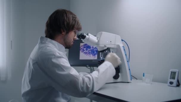 Cientista Masculino Olha Sob Microscópio Analisa Bactérias Amostra Sangue Laboratório — Vídeo de Stock