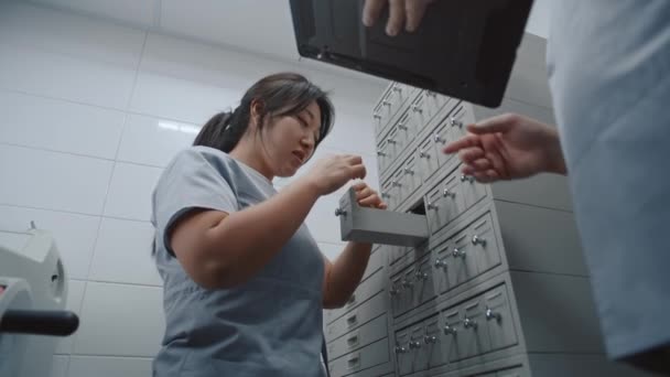亚洲护士在医疗储物柜中检查血液测试或组织学生物细胞分析样本 男医生使用平板电脑 医学专家 科学家在研究实验室工作 — 图库视频影像