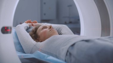 Tomografide, PET 'te ya da MRI taramasında yatarken ve makinenin içinde hareket ederken çekilmiş bir kadın portresi. İleri tıbbi teknolojileri olan bir hasta taranıyor. Yüksek teknolojili modern ekipmanlarla tıbbi laboratuvar..