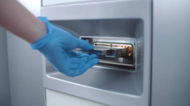 Bilim adamı numuneleri modern laboratuardaki mikrobiyolojik analiz cihazına koydu. Mikrobiyolog biyoteknoloji ya da ilaç araştırmaları yapıyor, hücreler ve bakteriler üzerinde çalışıyor, gelişmiş laboratuvar aşılarını geliştiriyor..