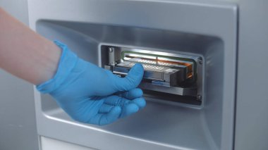 Bilim adamı numuneleri modern laboratuardaki mikrobiyolojik analiz cihazına koydu. Mikrobiyolog biyoteknoloji ya da ilaç araştırmaları yapıyor, hücreler ve bakteriler üzerinde çalışıyor, gelişmiş laboratuvar aşılarını geliştiriyor..