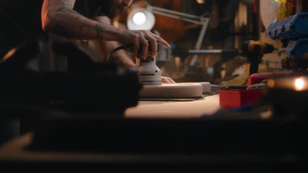 専門の男性大工は磨く機械を使用してテーブルの木製ギター ボディを磨きます 木工のマスター 職人は現代のワークショップで楽器を作ります ハンドメイドと起業家精神 — ストック動画