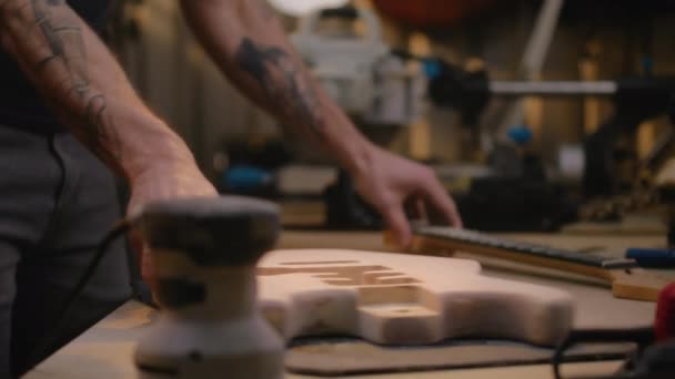 ギターの首をギターボディに固定する男性大工のクローズアップショット ウッドワーキングマスター 職人は現代のワークショップで楽器を作ります ハンドクラフトと中小企業コンセプト — ストック動画