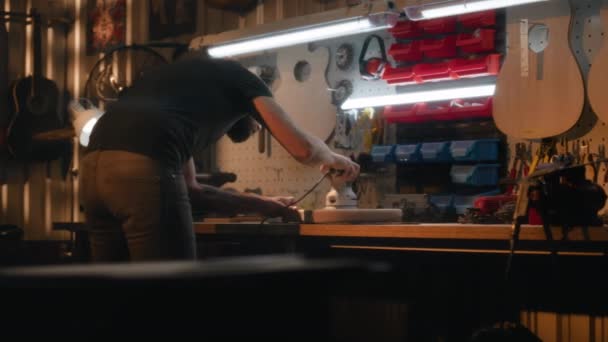 専門の男性職人は磨く機械を使用してテーブルの木製ギター ボディを磨きます 木工の専門家 大工は現代の研修会で楽器を作ります ハンドクラフトと中小企業 — ストック動画