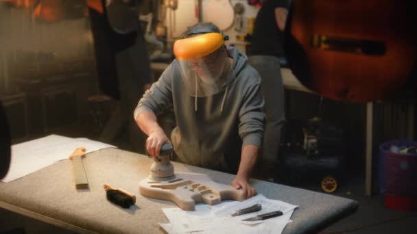 Kaukasische Reifen Handwerker Schutzmaske Schleift Gitarrenkörper Mit Schleifmaschine Handwerker Probiert — Stockvideo