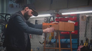 Erkek zanaatkar, esnaf ahşap komodinleri yapar ya da monte eder. Profesyonel marangoz modern mobilya atölyesinde çalışıyor. Duvarında alet ve teçhizat olan tahta. El işi ve küçük işletmeler..