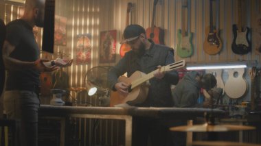 Modern atölyede iki marangoz ahşap gitar yapar. Marangozlar planlara bakarak müzik aleti yapmayı tartışıyorlar. İş arkadaşı arka planda çalışıyor. El işi ve küçük işletmeler..