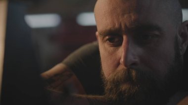 Orta yaşlı dövmeli bir zanaatkar işten sonra dinleniyor ve metronoma bakıyor. Profesyonel Kafkasyalı marangoz, karanlık atölyede masada oturur. El yapımı ve girişimcilik kavramı.