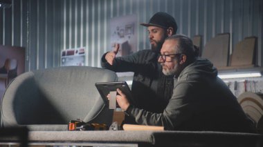 Olgun tasarımcı marangozla konuşur, sandalye tasarımı ve yapımı tartışır, dijital tablet bilgisayar kullanır. Profesyonel sanatçılar şık mobilya atölyelerinde çalışırlar. El işi ve küçük işletme konsepti.