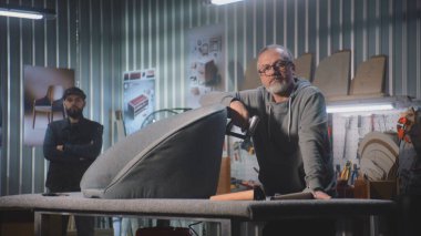 İki profesyonel marangoz, zanaatkarlar ayakta kameraya bakar. Mobilya montajı, yapımı veya yenilenmesi için modern ve şık bir atölye veya stüdyo. El yapımı ve girişimcilik konsepti. Portre.