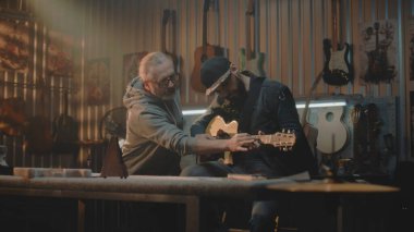 Müzisyen, şık bir garaj stüdyosunda metronomu dinleyerek gitar çalıyor. Olgun müzik öğretmeni sesi dinler ve insanlara müzik enstrümanı çalmayı öğretir. Duvarda el yapımı gitarlar asılı..