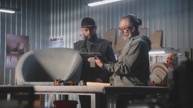 Olgun tasarımcı marangozla konuşur, sandalye tasarımı ve yapımı tartışır, dijital tablet bilgisayar kullanır. Profesyonel sanatçılar şık mobilya atölyelerinde çalışırlar. El işi ve küçük işletme konsepti.