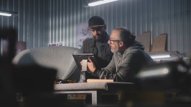 Olgun tasarımcı marangozla konuşur, sandalye tasarımı ve yapımı tartışır, dijital tablet bilgisayar kullanır. Profesyonel sanatçılar şık mobilya atölyelerinde çalışırlar. El işi ve küçük işletme konsepti.