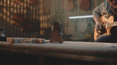 Olgun müzisyen, müzik enstrümanları yapmak için şık bir atölyede gitar çalar. Profesyonel marangoz ya da zanaatkar prodüksiyondan sonra gitarı kontrol eder. Duvarda el yapımı ahşap gitarlar asılı..