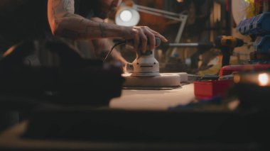 Profesyonel erkek marangoz parlatma makinesi kullanarak tahta gitar gövdesini parlatmış. Ahşap ustası, zanaatkar modern atölyede müzik aleti yapıyor. El yapımı ve girişimcilik..