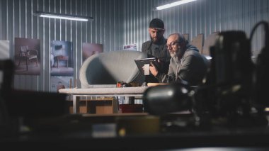 Olgun marangoz veya tasarımcı başka bir uzmanla konuşur, sandalye tasarımı ve yapımı hakkında konuşur, dijital tablet bilgisayar kullanır. Sanatçılar modern mobilya atölyesinde çalışırlar. El yapımı ve girişimcilik..