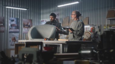 Olgun marangoz ya da tasarımcı dijital tablet bilgisayar kullanarak sandalye yapımı için hesaplamalar yapar, erkek meslektaşlarıyla istişarelerde bulunur. Sanatçılar modern mobilya atölyesinde çalışırlar. El yapımı ve girişimcilik.