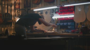 Profesyonel erkek zanaatkar, parlatma makinesi kullanarak tahta gitar gövdesini parlatmış. Ahşap ustası, marangoz modern atölyede müzik aleti yapıyor. El işi ve küçük işletmeler..