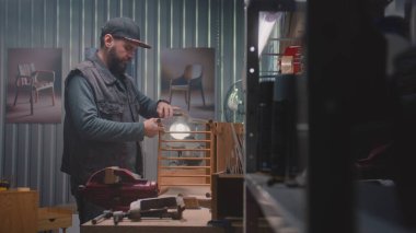 Profesyonel marangoz, profesyonel aletlerle LED lambanın altında ahşap komodin monte eder. Erkek zanaatkar, esnaf mobilya yapmak için modern atölyede çalışıyor. El işi ve küçük işletme konsepti.