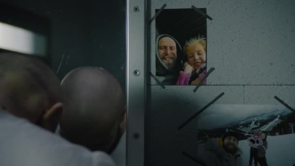 男囚犯站在监牢的镜子里看着自己 家人挂在镜子旁边的照片 犯人在狱中服刑 拘留中心或教养所 — 图库视频影像