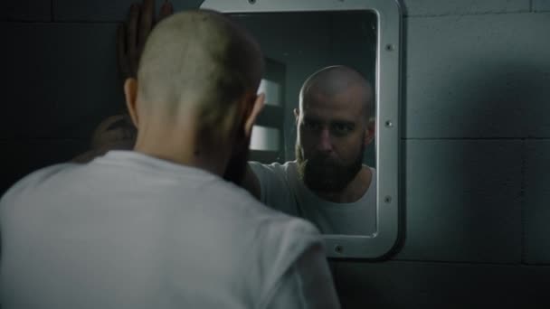 男性はタオルで顔を拭き取り 刑務所の鏡で自分自身を積極的に見ています 刑務所の刑務所で 刑務所に収監される 拘禁センターまたは矯正施設 — ストック動画