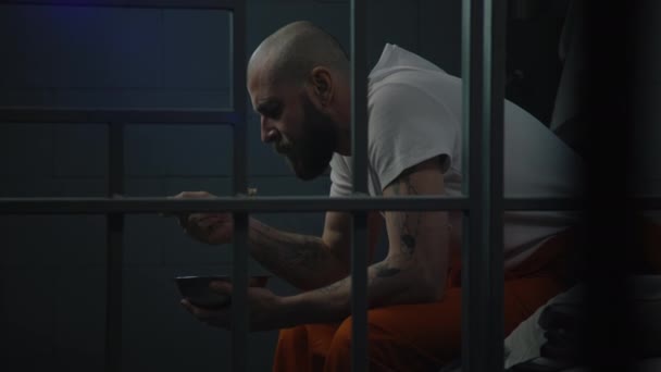 Muž Oranžové Uniformě Snaží Jíst Nechutné Vězeňské Jídlo Železné Mísy — Stock video