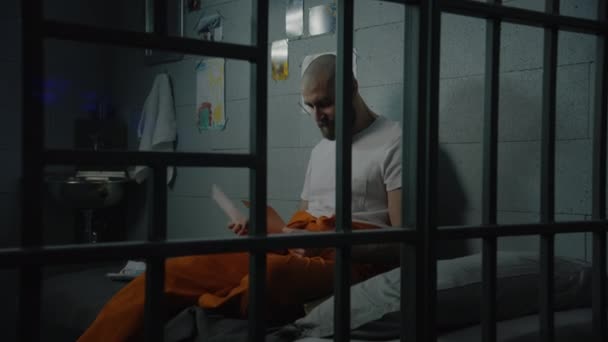 Prigioniero Maschio Uniforme Arancione Siede Sul Letto Cella Guarda Fotografie — Video Stock
