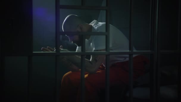 Criminal Orange Uniform Sits Bed Prison Cell Stands Looks Barred — Stock Video