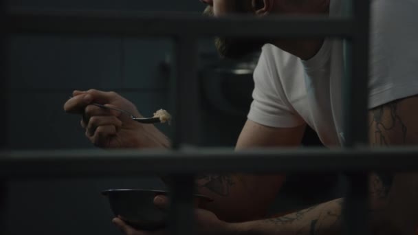 Чоловік Сидить Ліжку Камері Язнення Їсть Тюремну Їжу Залізної Чаші — стокове відео