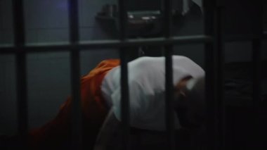 Turuncu üniformalı erkek mahkum ısınıyor, antrenman yapıyor ve hapishane hücresinde şınav çekiyor. Dövmeli suçlu ya da mahkum, hapiste suçtan hapis yatıyor. Gözaltı merkezi ya da ıslah evi.
