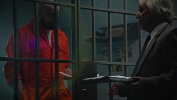 Gevangene Oranje Uniform Staat Achter Tralies Gevangenis Cel Praat Met — Stockvideo