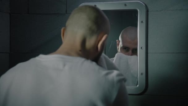 범죄자는 수건으로 얼굴을 세포의 거울에서 자신을 심각하게 봅니다 수감자는 감옥에서 — 비디오