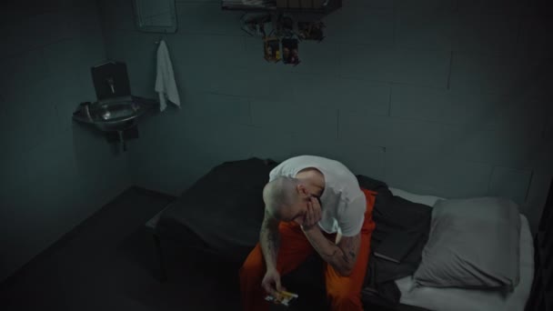 Gevangene Oranje Uniform Zit Bed Cel Kijkt Foto Crimineel Zit — Stockvideo
