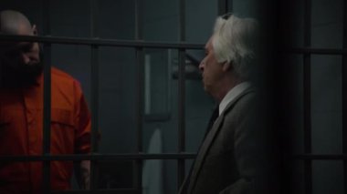Turuncu üniformalı bir mahkum hapishane hücresinde duruyor, avukatla konuşuyor, avukat sözleşmesi okuyor. Gangster hapiste suçtan hapis yatar. Gözaltı merkezi ya da ıslah evi.