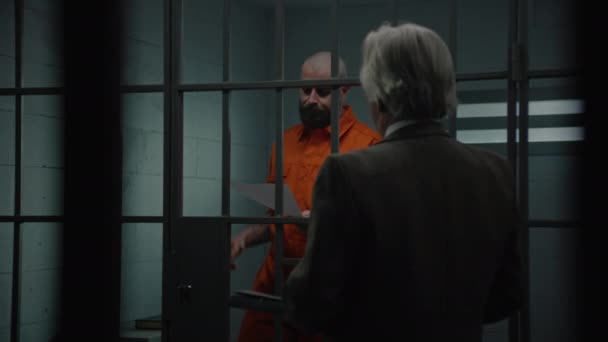Häftling Orangefarbener Uniform Steht Hinter Gittern Gefängniszelle Spricht Mit Anwalt — Stockvideo