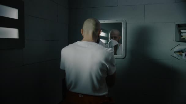 真面目な男性の囚人はタオルで顔を拭き 刑務所の鏡を見ている 違法に有罪判決を受けた男性は 刑務所で有罪判決を受けた 拘禁センターまたは矯正施設 — ストック動画