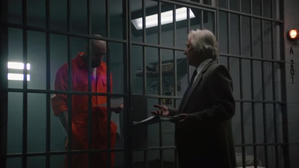 Turuncu Üniformalı Bir Suçlu Hapishane Hücresinde Duruyor Avukatla Konuşuyor Sözleşmeyi — Stok video