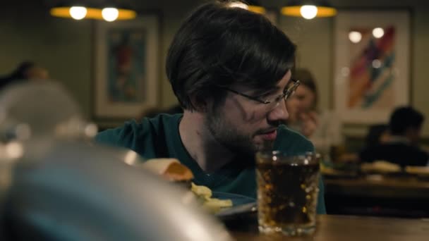 안경을 남자는 카운터에 마시고 먹습니다 배경에서 시간을 보내고 사람들은 사회화하고 — 비디오
