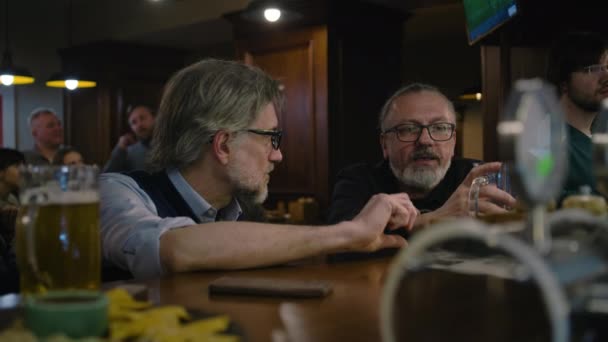 Dwóch Mężczyzn Rozmawia Pije Piwo Siedząc Przy Barze Dojrzali Fani — Wideo stockowe