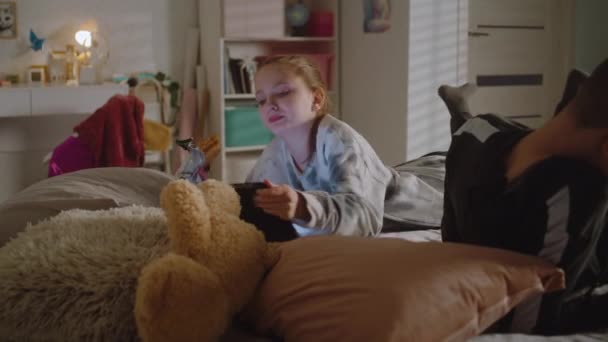 Flickan Ligger Sängen Äter Croissant Tittar Videoinnehåll Med Hjälp Surfplatta — Stockvideo