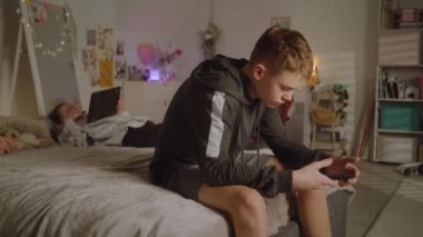Genç kız yatakta uzanıyor ve tablet kullanarak sosyal ağları parşömenlere döküyor. Elinde telefon olan çocuk oyun oynuyor. Gençler boş vakitlerini geçiriyorlar. Aile ilişkisi. Konforlu ve şık iç tasarımı olan bir ev..