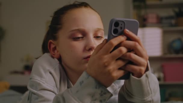 接近高加索青少年使用她的手机在社交网络上与朋友聊天 并在网上冲浪 小女孩躺在明亮的卧室里舒适的床上 青少年周末呆在家里 — 图库视频影像