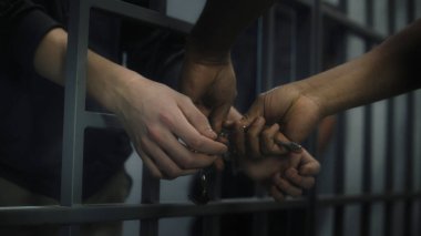Müdür genç mahkumun kelepçelerini çıkarır. Çok ırklı gençler ıslah evinde ya da gözaltı merkezinde hapis yatıyorlar. Hücredeki genç mahkumlar. Adalet sistemi. Kapat..