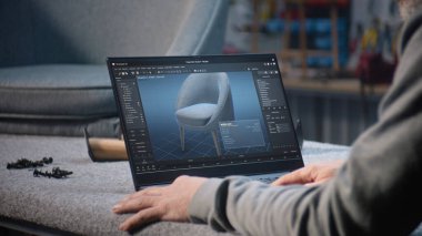 Yaratıcı adam, mobilya tasarımı ve dizüstü bilgisayarda çalışan 3D modelleme için profesyonel yazılım kullanır. Tasarımcı, şık ahşap sandalyenin dijital 3D modelini yaratıyor, marangozluk projesini hazırlıyor.
