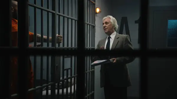 身穿橙色制服的罪犯靠在牢房的铁栏上 与律师交谈 阅读他的合同 犯人因犯罪在教养所服刑 Gangster Detention Centre — 图库照片