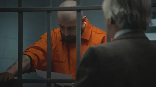 Prisoner Orange Uniform Leans Prison Cell Bars Talks Advocate Reads — Stock Photo, Image