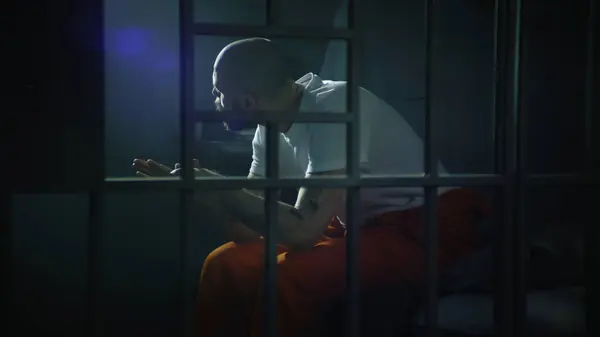 Criminal Orange Uniform Sits Bed Prison Cell Stands Looks Barred — Stock Photo, Image