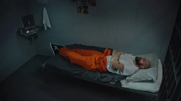 身穿橙色制服的囚犯躺在床上 站起来走进监牢 罪犯因犯罪而服刑 拘留中心或教养所的囚犯 司法系统 高角度 — 图库照片